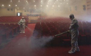 Workers wearing protective gears spray antiseptic solution as a precaution against the spread of MERS, Middle East Respiratory Syndrome, virus at an art hall in Seoul, South Korea, Friday, June 12, 2015. (Credit: AP Photo)