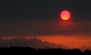 In August 2015, the sun turns red as it sets through the smoke behind the Olympic Mountains in Central Washington. Wildfires in the state left a black, smoky haze hanging over the entire area. (Credit: © Larry Steagall, Kitsap Sun/AP Photo)