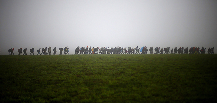 A group of migrants make their way over a meadow after crossing the border between Austria and Germany in Wegscheid near Passau, Germany, in October 2015. Credit: © Matthias Schrader, AP Photo