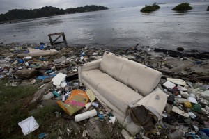 In this June 1, 2015 photo, a discarded sofa litters the shore of Guanabara Bay in Rio de Janeiro, Brazil. As part of its Olympic bid, Brazil promised to build eight treatment facilities to filter out much of the sewage and prevent tons of household trash from flowing into the Guanabara Bay. Only one has been built. Tons of household trash line the coastline and form islands of refuse.  Credit: © Silvia Izquierdo, AP Photo