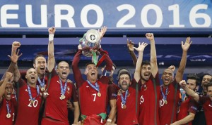 Portugal's Cristiano Ronaldo, center, and teammates with the trophy after the Euro 2016 final soccer match between Portugal and France at the Stade de France in Saint-Denis, north of Paris, Sunday, July 10, 2016. Credit: © Frank Augstein, AP Photo
