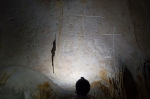 A researcher shines light on inscriptions of crosses above the name Jesus (in Latin) in the soft limestone wall of Cave 18 on Mona Island, Puerto Rico.Inscribed into soft limestone early in the Spanish colonial period, the three crosses of Calvary appear above the name of Jesus, in Latin, in one of the many caves on Mona Island. Credit: © Jago Cooper, The British Museum/University of Leicester