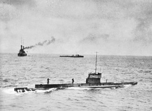 Royal Australian Navy submarine AE1 (foreground), HMAS Australia (left background) and a River class destroyer (centre background) at a rendezvous off Rossell Island before proceeding to Rabaul. The photograph was taken from the bridge of HMAS Encounter, when mail was being delivered to the fleet. 9 September 1914 . Credit: Australian War Memorial