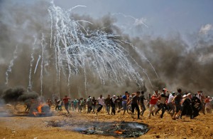 Palestinians run for cover from tear gas during clashes with Israeli security forces near the border between Israel and the Gaza Strip, east of Jabalia on May 14, 2018, as Palestinians protest over the inauguration of the US embassy following its controversial move to Jerusalem.  Credit: © Mohammed Abed, AFP/Getty Images