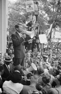 On June 14, 1963, attorney General Robert F. Kennedy speaking to a crowd of African Americans and whites through a megaphone outside the Justice Department; sign for Congress of Racial Equality is prominently displayed.  Credit: Library of Congress