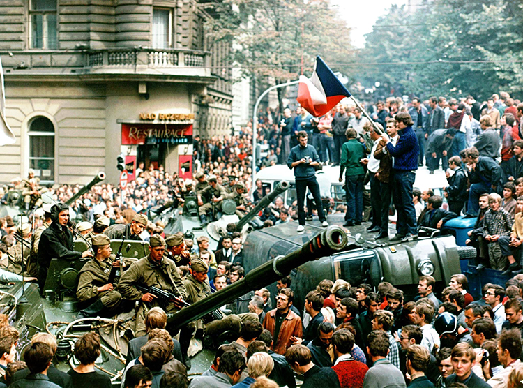 Czech youngsters holding Czechoslovakian flags stand atop of an overturned truck as other Prague residents surround Soviet tanks in downtown Prague on Aug. 21, 1968, as a Soviet-led invasion by the Warsaw Pact armies crushed the so-called Prague Spring reform in former Czechoslovakia 30 years ago. Credit: © Libor Hajsky, CTK/AP Photo