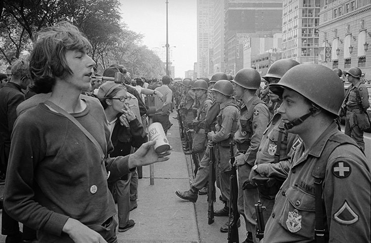 Young "hippie" standing in front of a row of National Guard soldiers, across the street from the Hilton Hotel at Grant Park, at the Democratic National Convention in Chicago, August 26, 1968. Credit: Library of Congress