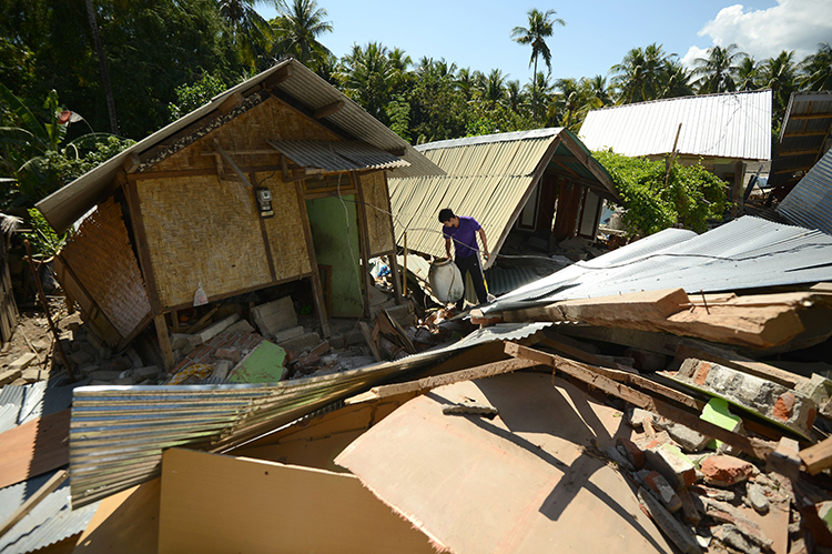A man looks at items by damaged houses at Pemenang village in northern Lombok in West Nusa Tenggara province on August 7, 2018, two days after the area was struck by an earthquake. - The shallow 6.9-magnitude quake killed at least 105 people and destroyed thousands of buildings in Lombok on August 5, just days after another deadly tremor surged through the holiday island and killed 17.  Credit: © Sonny Tumbelaka, AFP/Getty Images