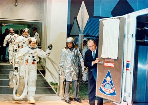 The Apollo 8 crew leaves the Kennedy Space Center's (KSC) Manned Spacecraft Operations Building (MSOB) during the Apollo 8 prelaunch countdown. Astronaut Frank Borman (waving to well-wishers), commander, leads followed by astronauts James A. Lovell Jr., command module pilot; and William A. Anders, lunar module pilot. The crew is about to enter a special transfer van which transported them to Pad A, Launch Complex 39, where their Apollo 8 (Spacecraft 103/Saturn 503) space vehicle awaited them. Liftoff for the lunar orbit mission was at 7:51 a.m. (EST). Holding the door to the transfer van is Charles Buckley, KSC security chief. Credit: JSC/NASA