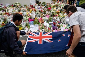 Students display the New Zealand national flag next to flowers during a vigil in Christchurch on March 18, 2019, three days after a shooting incident at two mosques in the city that claimed the lives of 50 Muslim worshippers. - New Zealand will tighten gun laws in the wake of its worst modern-day massacre, the government said on March 18, as it emerged that the white supremacist accused of carrying out the killings at two mosques will represent himself in court.  Credit: © Anthony Wallace, AFP/Getty Images