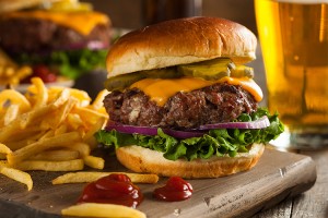 A hamburger is a flattened ground beef patty between two halves of a bun or slices of bread. It is one of the most popular sandwiches in the world. The hamburger in this photo is dressed with lettuce, red onions, cheese, and pickles, with French fries and ketchup on the side. Credit: © Brent Hofacker, Shutterstock 