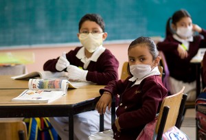 Schoolchildren wearing protective masks attend class at an elementary school in Mexico City May 11, 2009. Millions of Mexican elementary and junior high school students began returning to classes on Monday morning for the first time since April 23 when the government closed schools to prevent infection with the new flu strain of H1N1 flu, formerly known as swine flu. Credit: © Jorge Dan, Reuters
