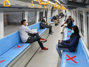 People sit on designated areas decided by red cross marks to ensure social distancing inside a light rapid transit train in Palembang, South Sumatra on March 20, 2020, amid concerns of the COVID-19 coronavirus outbreak.  Credit: ABDUL QODIR/AFP via Getty Images