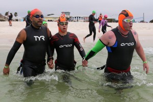 Chris Nikic, center, is helped into the water by his guide Dan Grieb, right,  in the swimming portion of the Florida Ironman triathlon on Nov. 7, 2020, in Panama City Beach. Nikic became the first person with Down syndrome to finish a grueling Ironman triathlon. Credit: © Bachman/Getty Images for IRONMAN