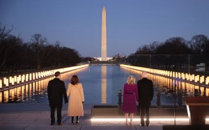 L-R) Douglas Emhoff, U.S. Vice President-elect Kamala Harris, Dr. Jill Biden and U.S. President-elect Joe Biden look down the National Mall as lamps are lit  to honor the nearly 400,000 American victims of the coronavirus pandemic at the Lincoln Memorial Reflecting Pool January 19, 2021 in Washington, DC. As the nation's capital has become a fortress city of roadblocks, barricades and 20,000 National Guard troops due to heightened security around Biden's inauguration, 200,000 small flags were installed on the National Mall to honor the nearly 400,000 Americans killed by COVID-19. Credit: © Chip Somodevilla, Getty Images