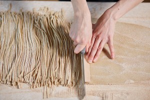 A noodlemaker makes noodles by hand, using the roll-and-cut method. The dough is rolled out flat and then cut into long strips. Credit: © Lyashenko Egor, Shutterstock
