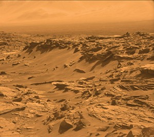A Martian landscape includes jagged rocks, sand dunes, and hazy clouds. The image, taken by the United States rover Curiosity, has been adjusted to show the natural color of the planet, as it would appear to an observer on the surface. Credit: NASA/JPL-Caltech/MSSS